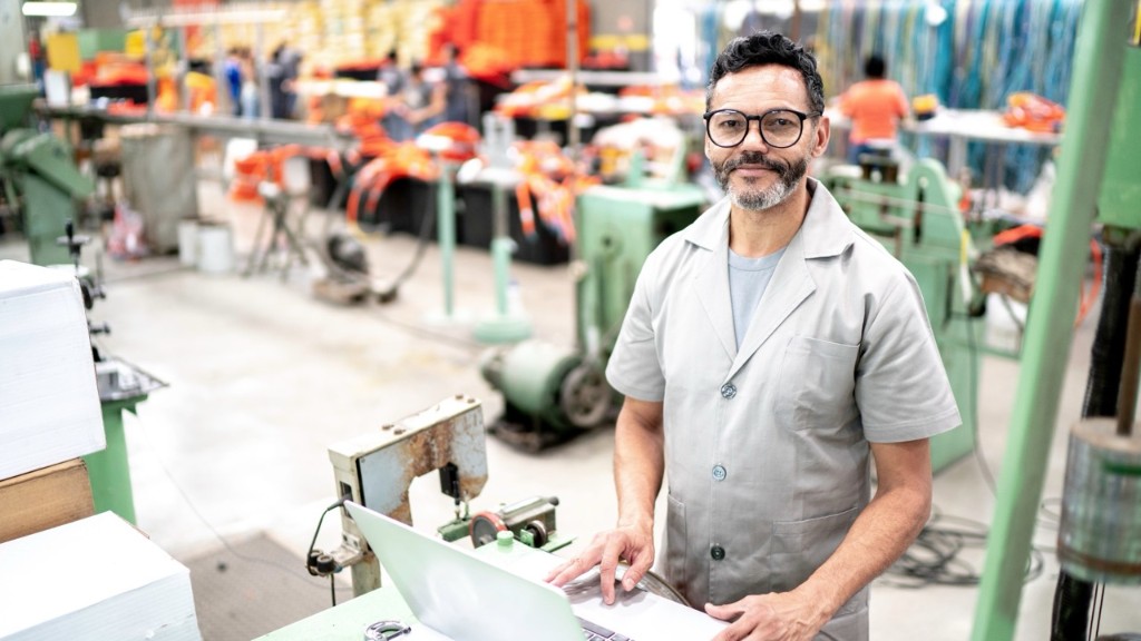 Unternehmer in einer Produktion nutzt Skorix am Laptop